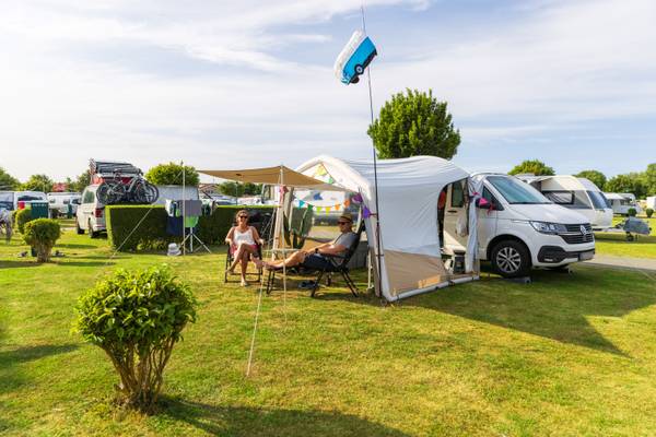 Dos personas descansando fuera de una tienda de campaña en el camping Insel-Camp Fehmarn.