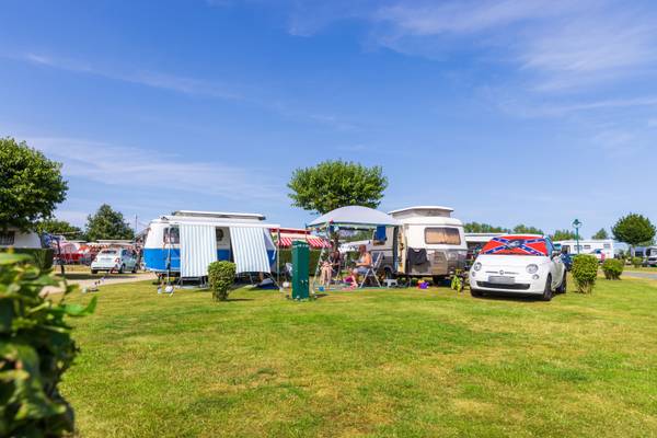 Un camping con varias caravanas y una familia disfrutando de un día soleado.