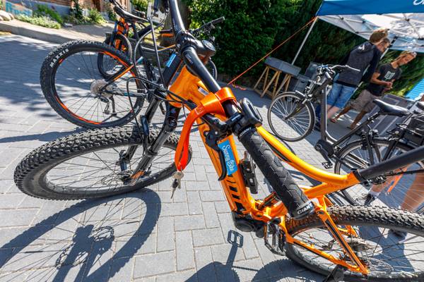 Bicicleta naranja en el camping con personas en el fondo.