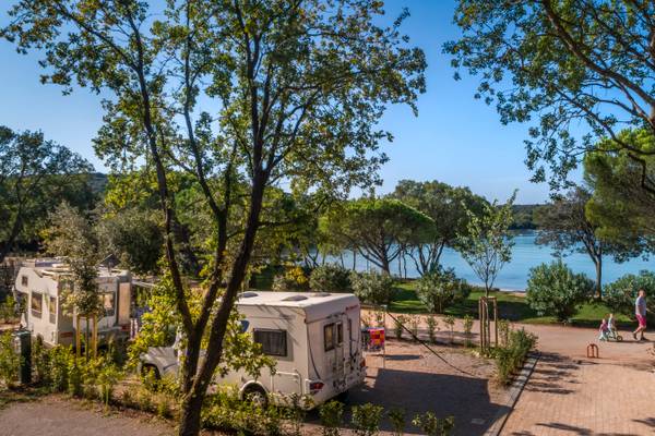 Camping avec des camping-cars et des enfants près d'un lac.