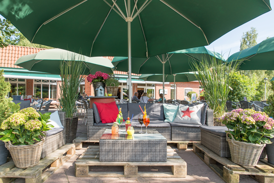 Terras med siddepladser under paraplyer på Sudsee Camp campingplads