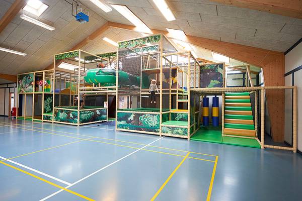 Zona de juegos para niños en Jambo Feriepark con estructuras de escalada verdes y amarillas.