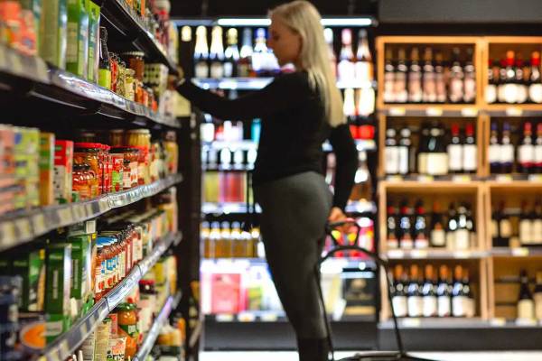 Frau beim Einkaufen im Supermarkt, nimmt Artikel von den Regalen.