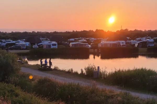 Sonnenuntergang am Campingplatz Hvidbjerg Strand Feriepark mit Leuten, die am See angeln.