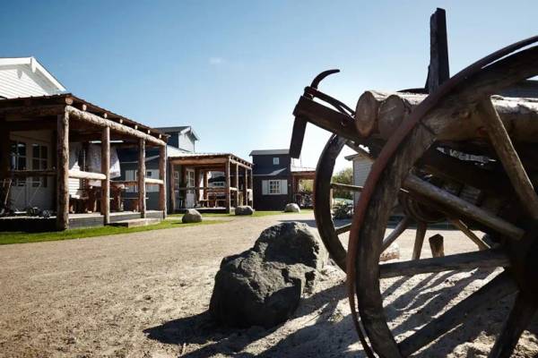 Hvidbjerg Strand Feriepark Campingplatz mit Blockhütten und einer Wagenrad im Vordergrund.