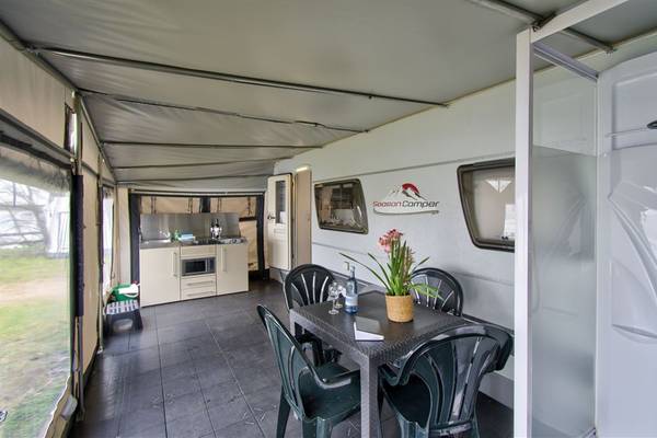 Interior of a camping mobile with a table, chairs, and flowers.