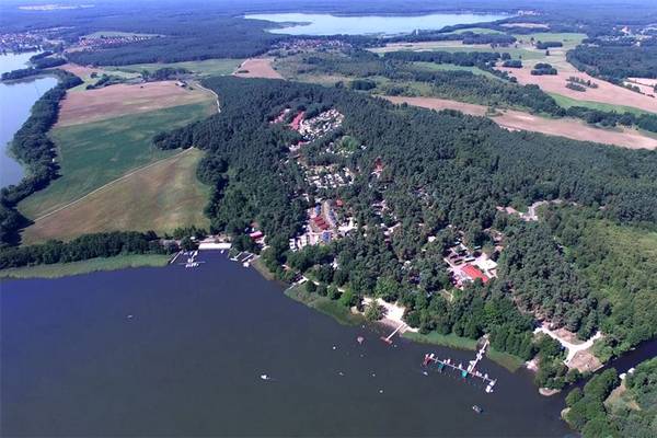 Luftfoto af Camping- und Ferienpark Havelberge med træer, sø og bygninger.