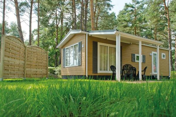 Camping and holiday park Havelberge vacation home surrounded by trees with a table and chairs