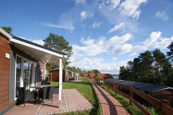 Exterior view of Camping- und Ferienpark Havelberge with a house, patio, and pathway leading to the lake.