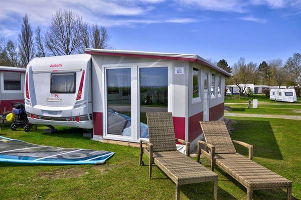 Campingplatz Wulfener Hals mit einem weißen und roten Wohnwagen auf dem Rasen.