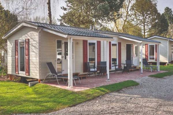 Eine Reihe von Mobilheimen auf dem Campingplatz Wulfener Hals mit Terrassenmöbeln.