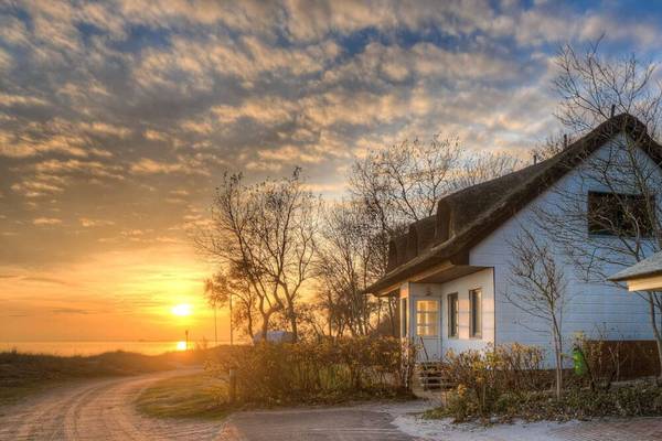 Sonnenuntergang am Wulfener Hals Campingplatz mit einem traditionellen Haus im Vordergrund.