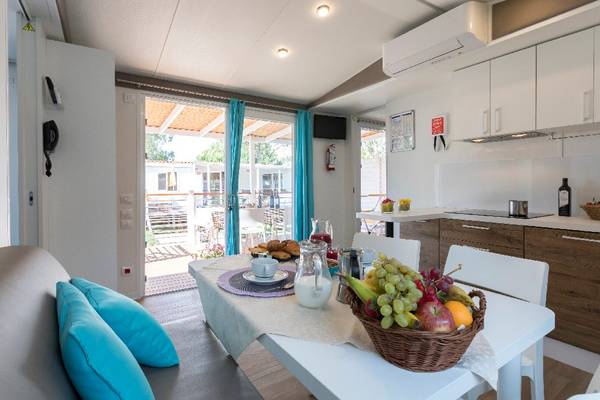 Interieur van een campingkeuken met eethoek en fruitmand op tafel.