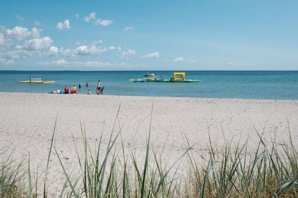 Una vista de la playa del Campamento Feddet Strand Resort con personas y juguetes de agua inflables