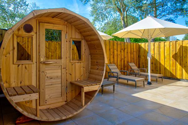 Eine Holzsauna mit Sitzbänken und einem großen Sonnenschirm im Freien.