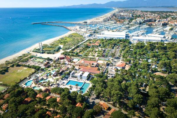 Aerial view of Camping Village Le Brasilia, showing a beach, marina, and resort facilities.