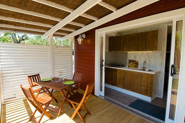 Terraza de una cabaña de madera en el camping Nature Parc L`Ardéchois con mesa y sillas.