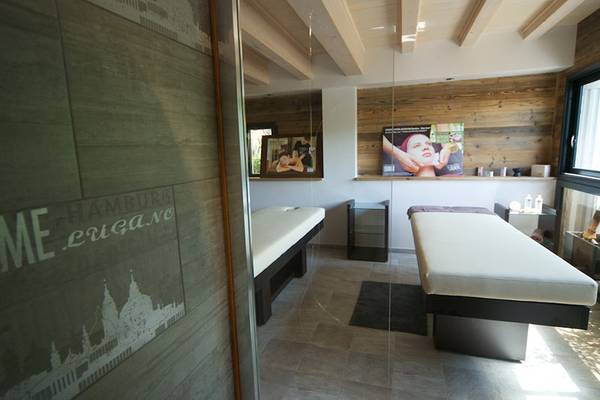 Sala de tratamiento en el hotel con dos camas y una pared de piedra.