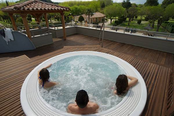 Tres personas relajándose en un jacuzzi en una terraza de un camping.