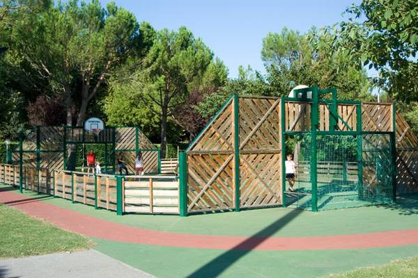 Parque recreativo al aire libre con canasta de baloncesto y parque infantil.