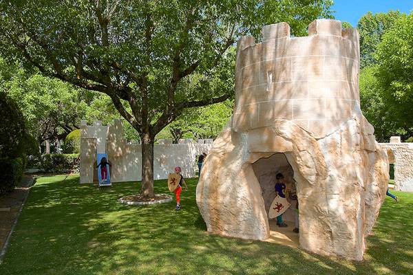 Niños jugando en un área de juegos temática de castillo en un camping.