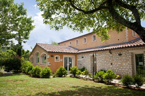Vista exterior del camping Nature Parc L'Ardéchois con techo de tejas y paredes de piedra.