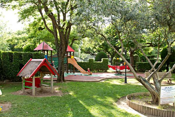 Zona de juegos infantiles en el camping Nature Parc L'Ardéchois con tobogán y estructura de escalada.