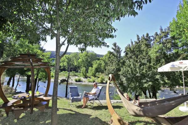 Camping Nature Parc L`Ardéchois con hamaca y mesa junto al río.