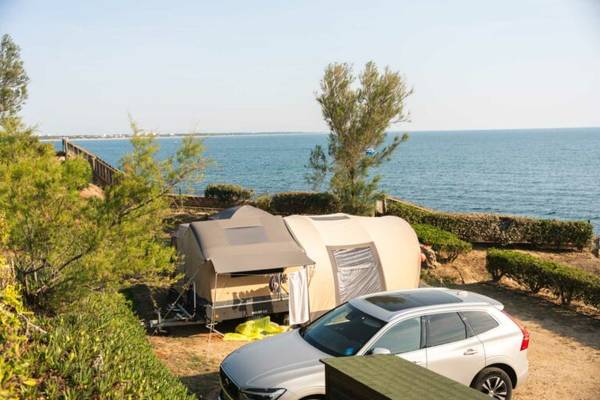 Campingplatz am Meer mit Auto und Zelt, Blick auf den Ozean.