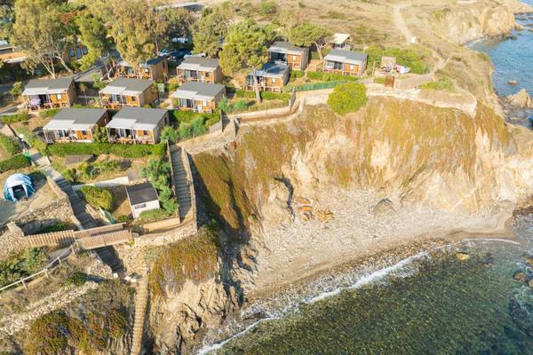 Luftaufnahme von Camping Les Criques de Porteils mit Chalets auf einem Klippenüberblick über das Meer.
