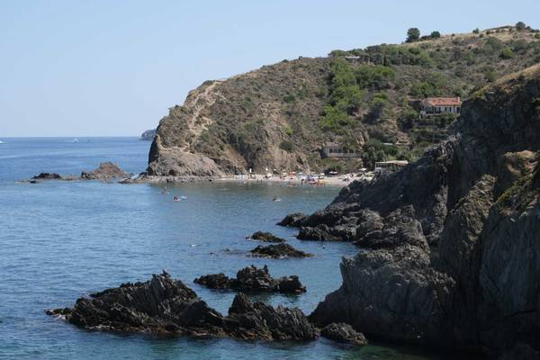 Camping Les Criques de Porteils Strand mit Schwimmenden und einem Haus auf einem Felsen.