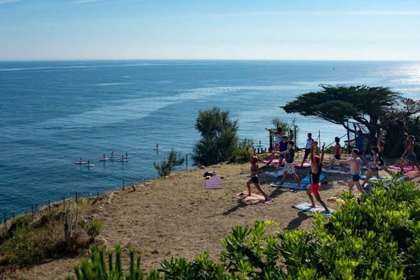 Yoga-Sitzung am Strand mit Blick auf den Ozean im Camping Les Criques de Porteils.
