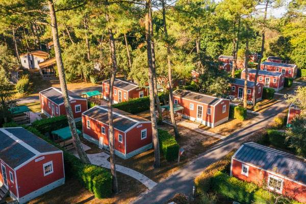 Luchtfoto van Camping Village Sylvamar met rode hutten omgeven door bomen.