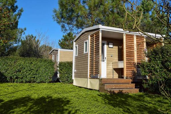 Twee houten stacaravans in Camping Village Sylvamar, omgeven door groen.