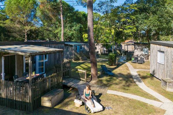 Luchtfoto van een camping met verschillende hutten en een vrouw op een ligstoel