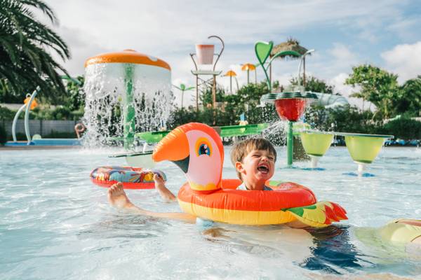 Dreng i pool med oppustelig flamingo-ring
