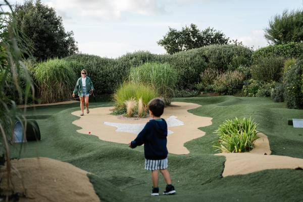 Barn og voksen spiller minigolf i Camping Village Les Mouettes