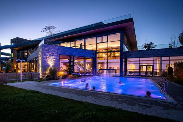 Vista nocturna del Sportcamp Woferlgut con una piscina exterior y un tobogán acuático iluminados.