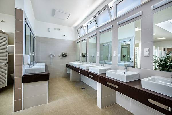 Baño público en el Turiscampo Camping Club Algarve con lavabos y espejos blancos.
