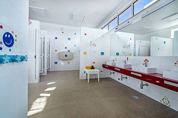 Baño infantil en el Turiscampo Camping Club Algarve con azulejos coloridos y lavabos.