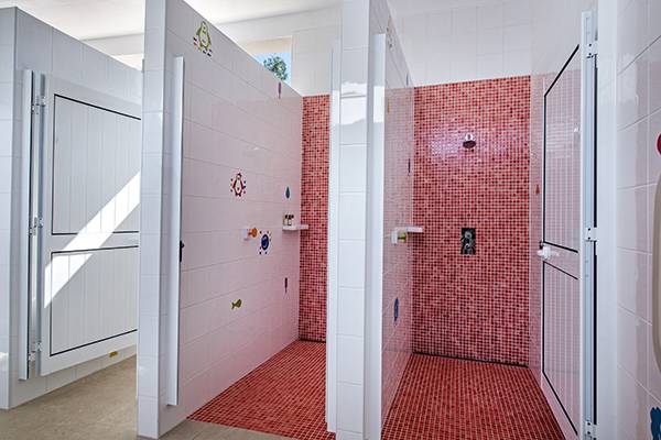 Área de ducha en el Turiscampo Camping Club Algarve con azulejos rojos y paredes blancas.