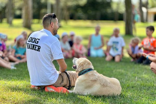 Entrenador de perros enseñando a niños en el camping Union Lido Mare