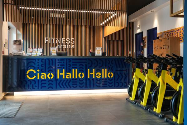 Recepción del Fitness Arena en el camping Union Lido Mare, con un banner azul y Ciao Hallo Hello en amarillo.