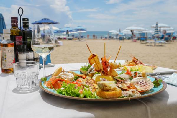 Plato de mariscos con vino en la playa en el camping Union Lido Mare.