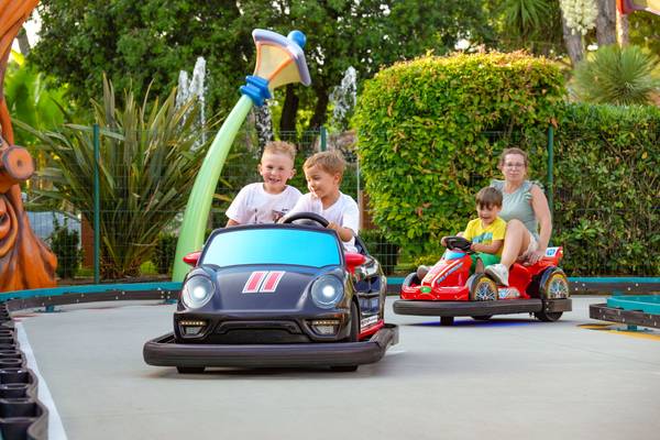 Tres niños y una mujer adulta montando en autos de choque en el campamento Union Lido Mare.