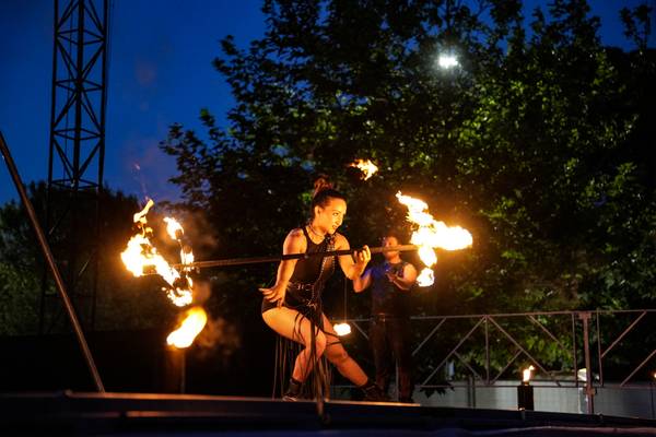 Show de fuego en el camping Union Lido Mare de noche con una mujer haciendo malabares con fuego y un hombre detrás de ella.