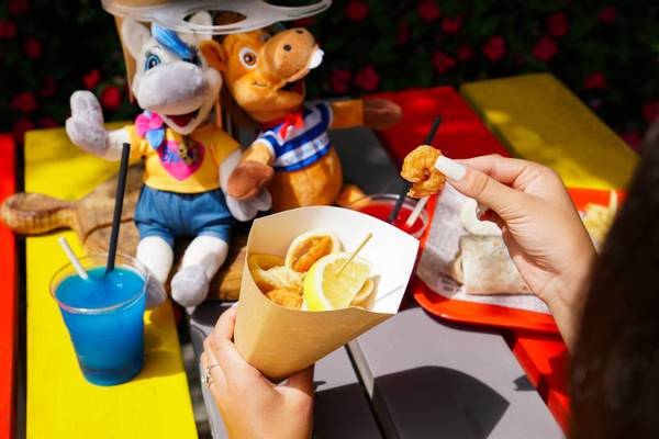 En el camping Union Lido Mare, una persona disfruta de un aperitivo con una bebida azul y peluches al fondo.