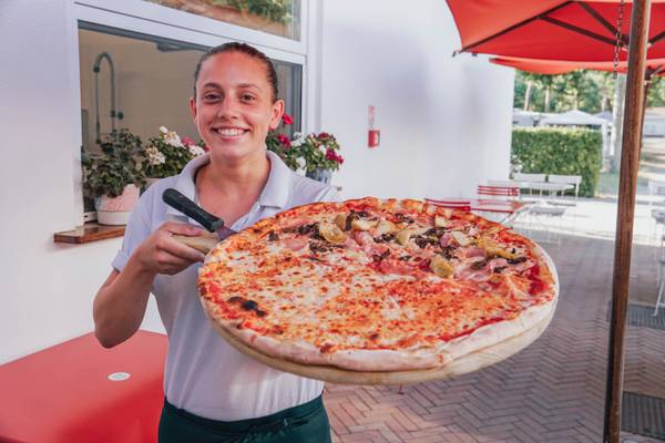 Mujer sosteniendo una pizza grande en el camping Union Lido Mare.