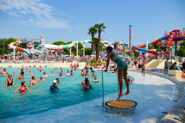 Parque acuático abarrotado con toboganes y una mujer en un trampolín