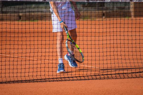 Jugador de tenis de pie cerca de la red en el camping Union Lido Mare.